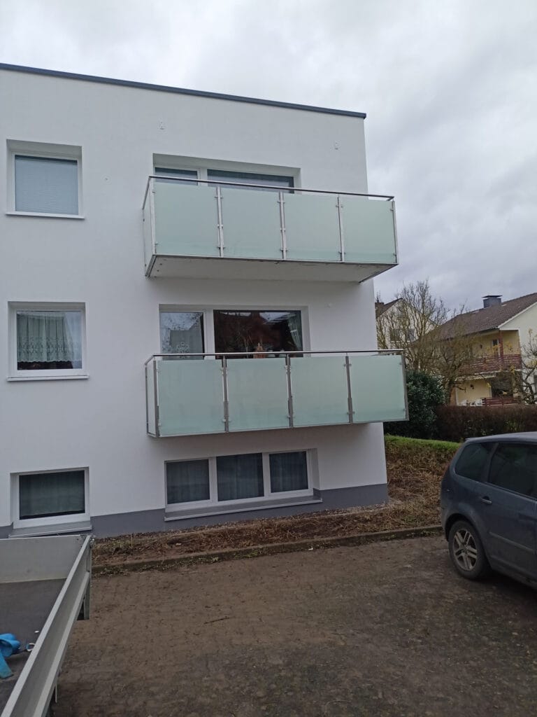 Zwei Balkone mit Edelstahlgeländern und satinierten Glasfüllungen an einem Wohnhaus