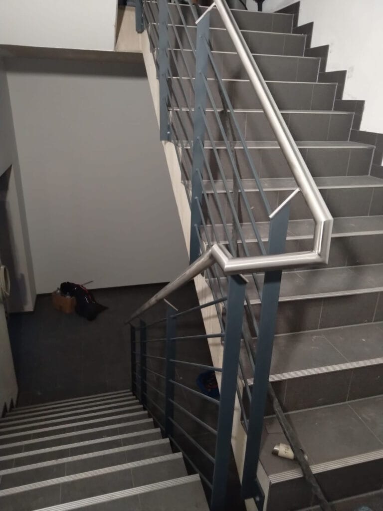 Metallgeländer mit Edelstahlhandlauf an einer gefliesten Innentreppe